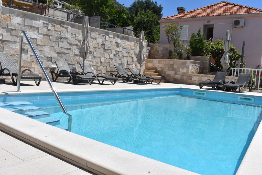 una piscina azul con sillas y una pared en Apartments Marlin Blue en Dubrovnik