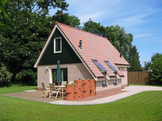 uma pequena casa com uma mesa e cadeiras num quintal em Koperwiek Texel em Den Burg