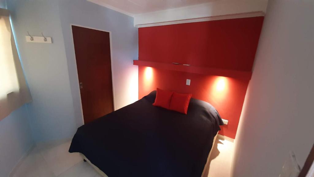 1 dormitorio con cama negra y almohada roja en Departamento cómodo, muy iluminado y bien ubicado. en Paraná