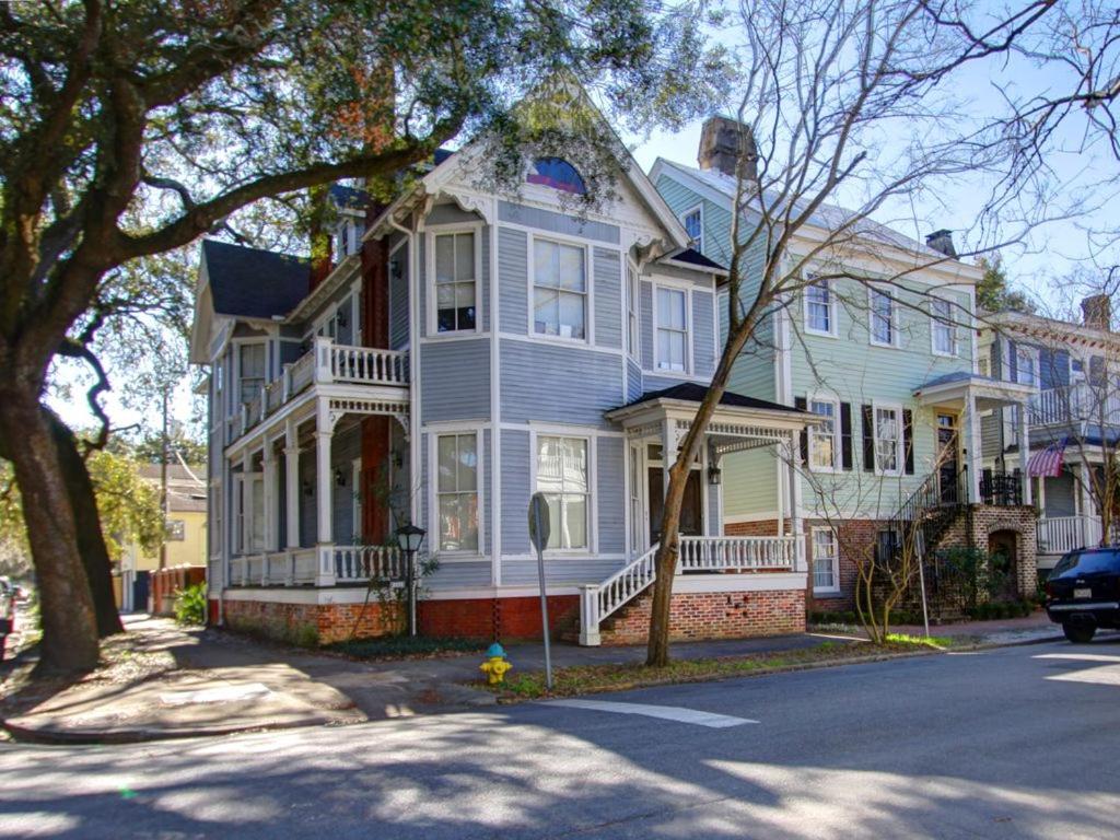 ein großes Haus auf einer Straße mit einem Auto davor geparkt in der Unterkunft Big Blue House - Near Forsyth Park - Lower Unit in Savannah
