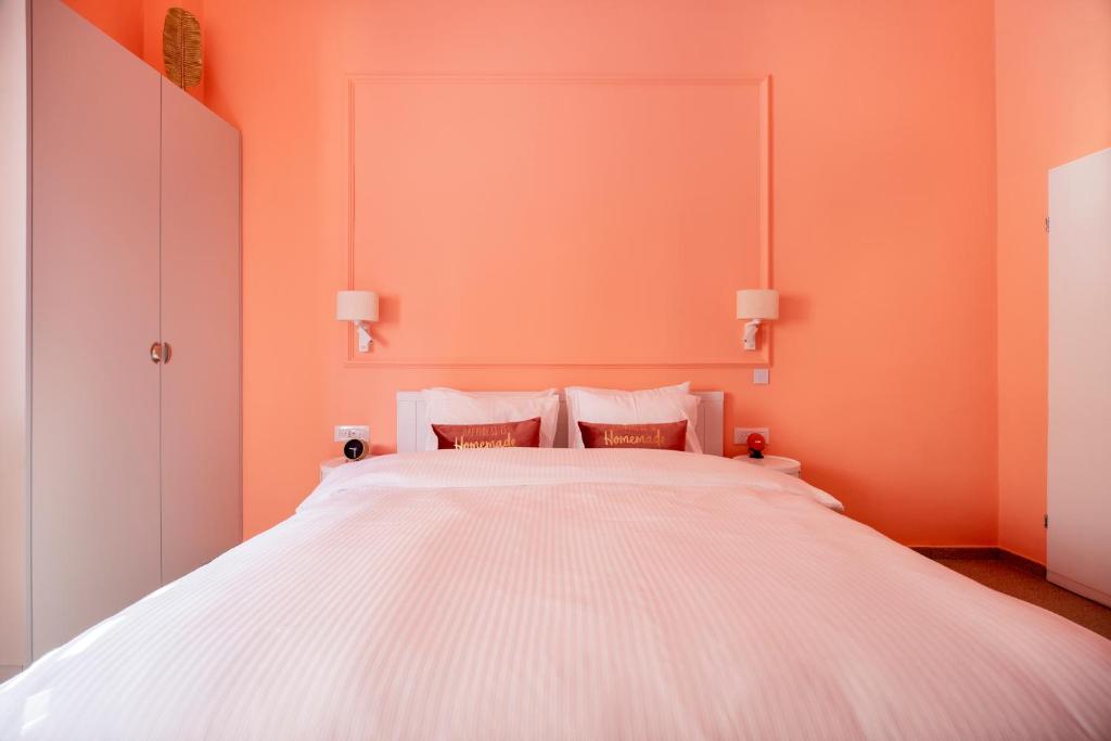 a bedroom with a large white bed with orange walls at Glamorous Pink Pearl Studio/Beach/Parking/Netflix in Tel Aviv