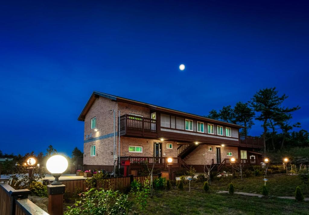 Una casa de noche con la luna en el cielo en J&J pension en Seogwipo