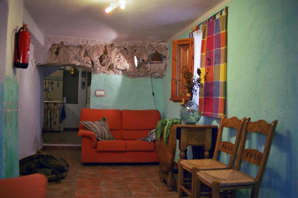 sala de estar con sofá naranja y mesa en Casa Rural Albayacín, en Letur