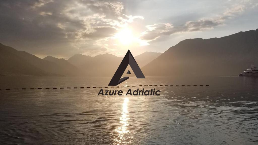 un logotipo sobre el agua con montañas al fondo en Apartments Azure Adriatic, en Kotor