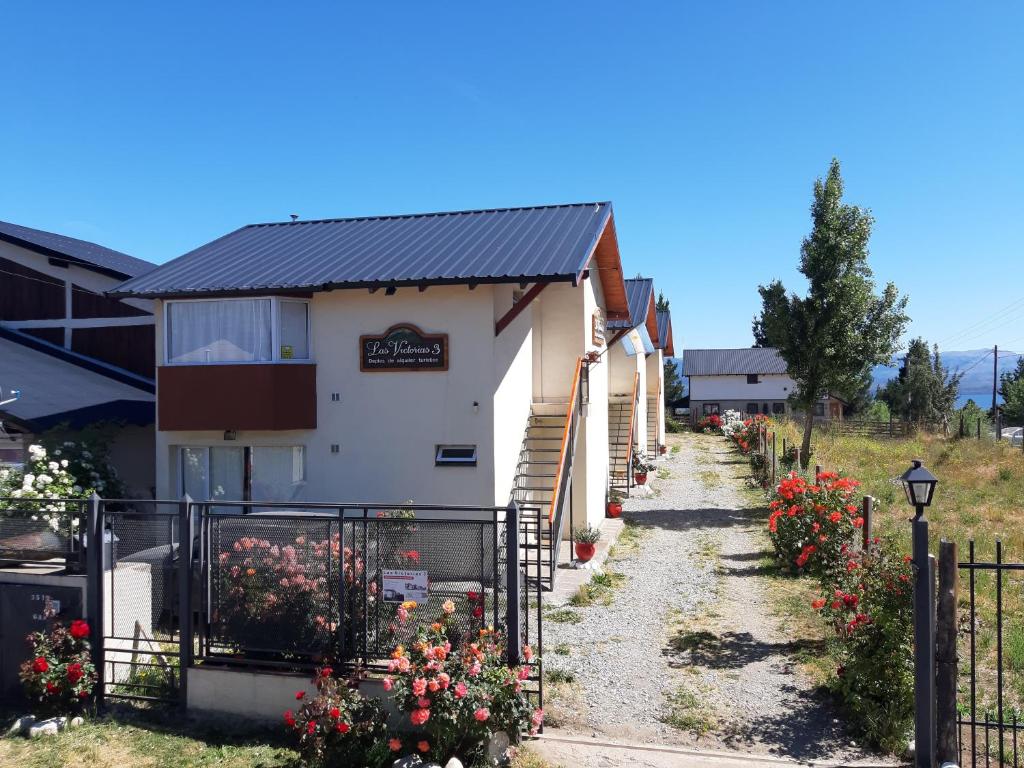 una casa con una valla y flores delante de ella en Las Victorias 3 en San Carlos de Bariloche