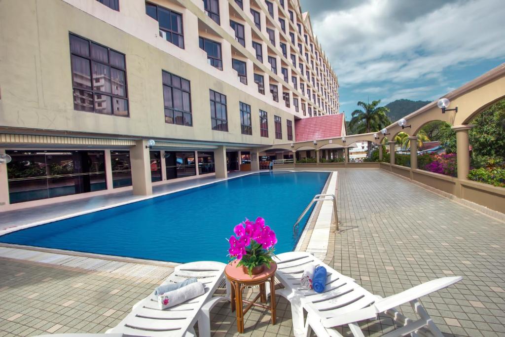 um hotel com piscina e cadeiras e um edifício em Hotel Grand Continental Langkawi em Kuah