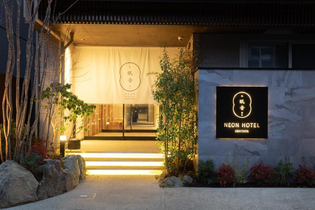 een bord op de voorkant van een nieuwe waarde winkel bij Neon Hotel in Kanazawa