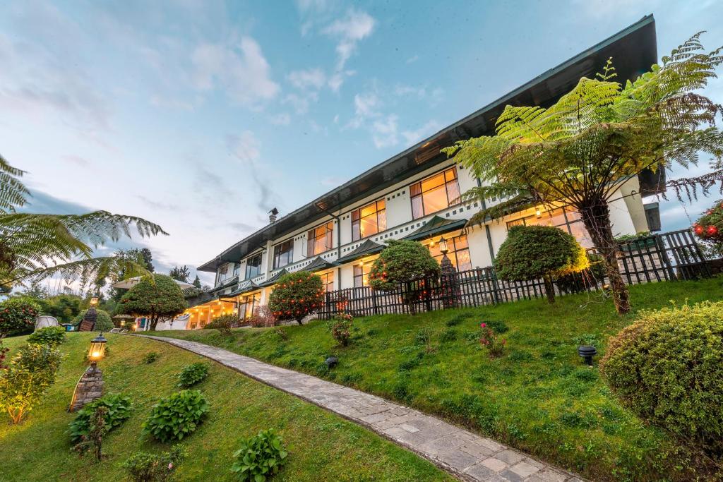 a building on a grassy hill next to a building at The Elgin Mount Pandim - Heritage Resort & Spa in Pelling