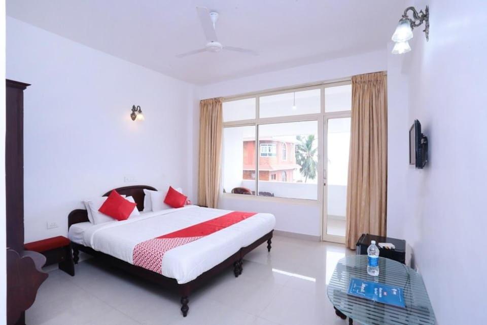 a bedroom with a bed and a large window at Swapnatheeram Beach Resort in Kovalam