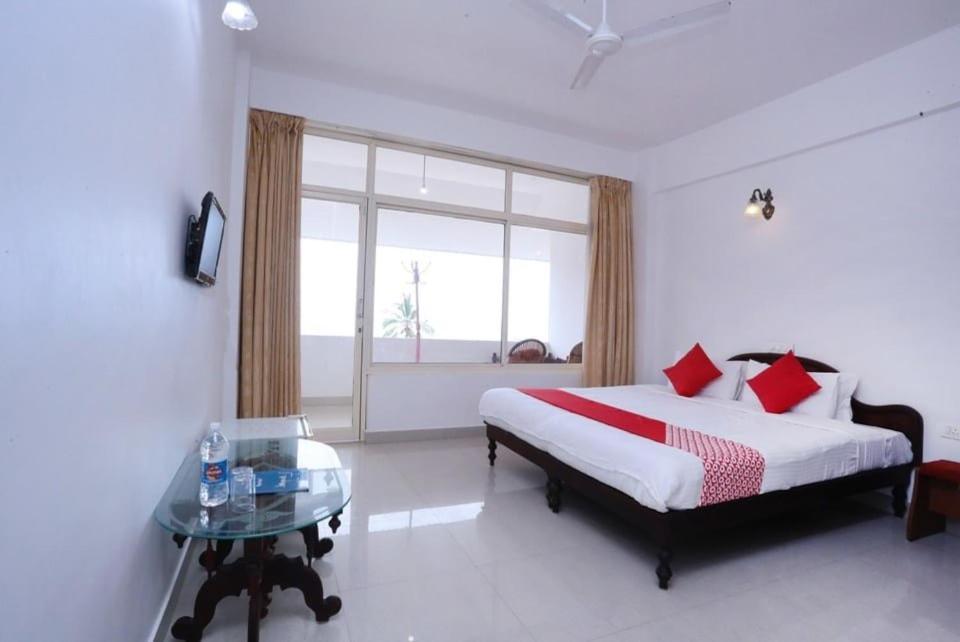 a bedroom with a bed and a table and a window at Swapnatheeram Beach Resort in Kovalam