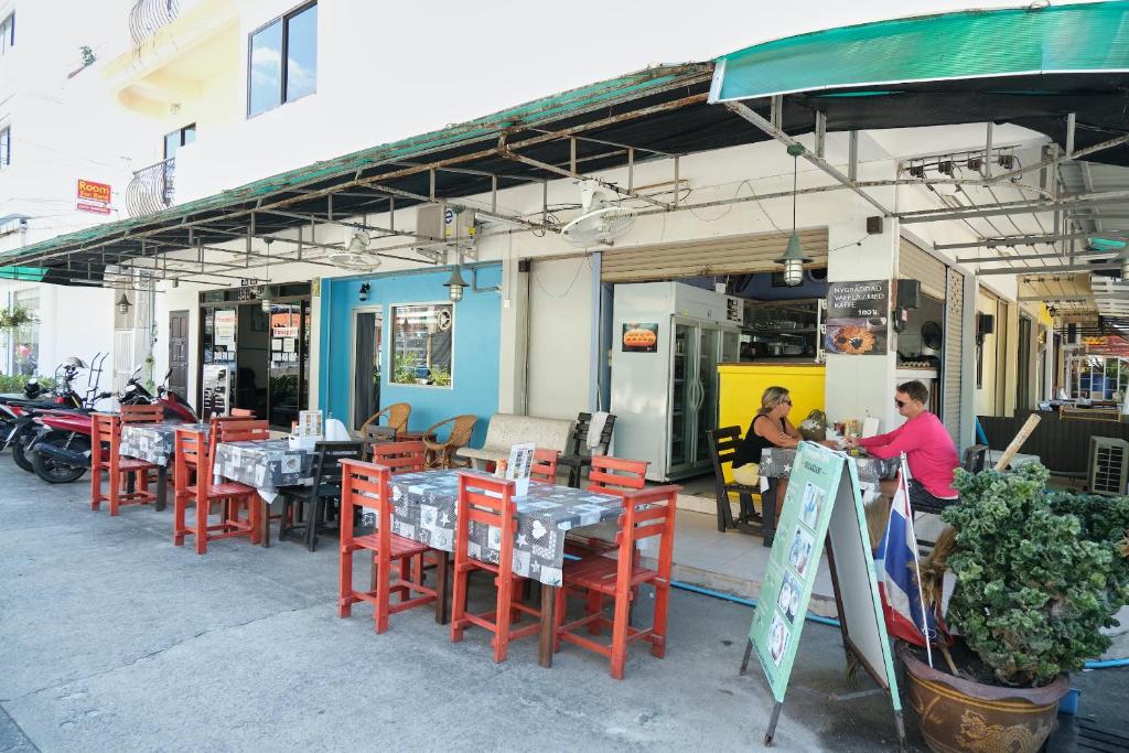 un restaurante con mesas y sillas y gente sentada en él en Pineapple Guesthouse en Karon Beach