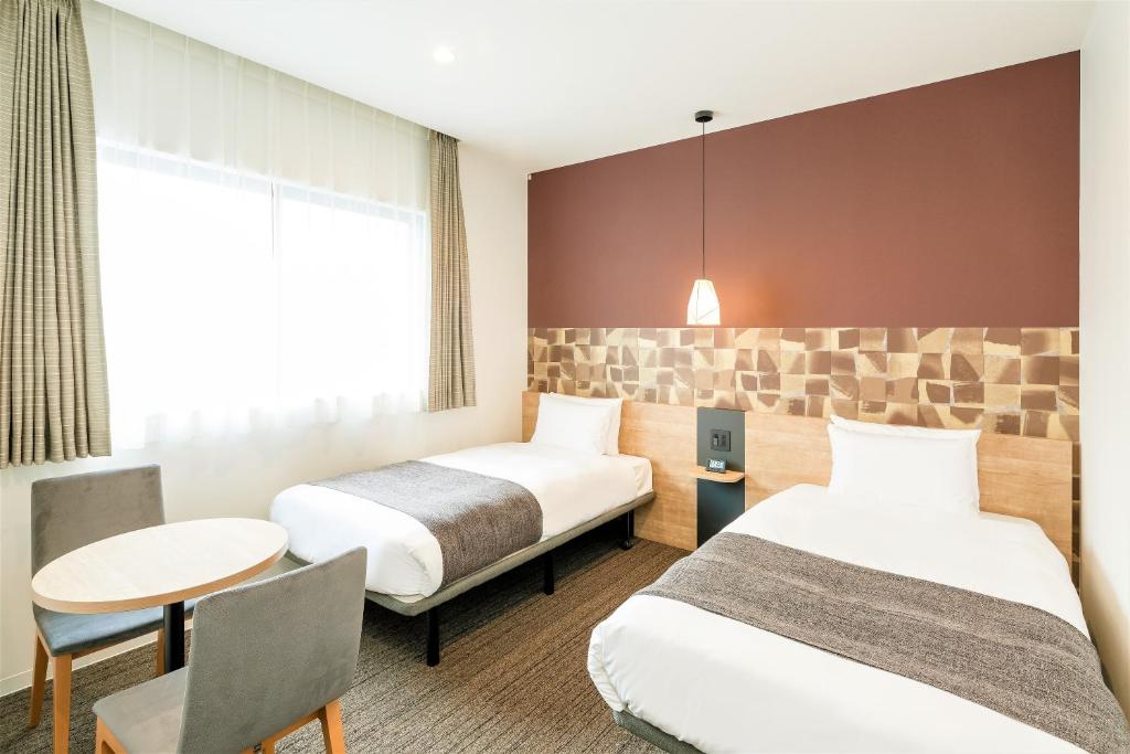 um quarto de hotel com duas camas e uma mesa em M's Hotel Sanjo Wakoku em Quioto