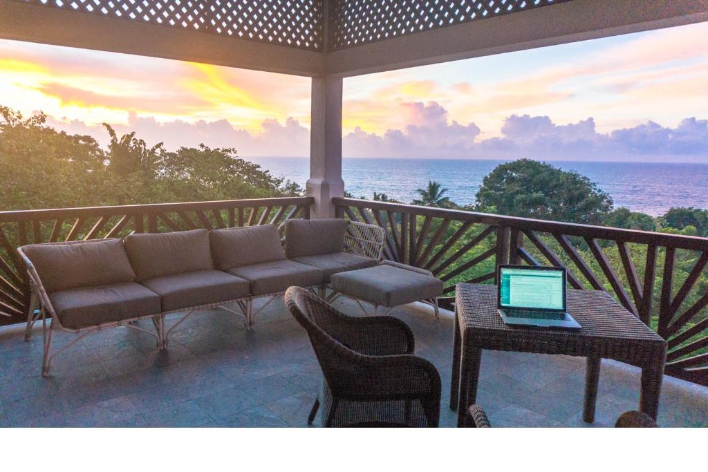 une terrasse couverte avec un canapé et une table munie d'un ordinateur portable. dans l'établissement Little Tamarind, à Tangalle