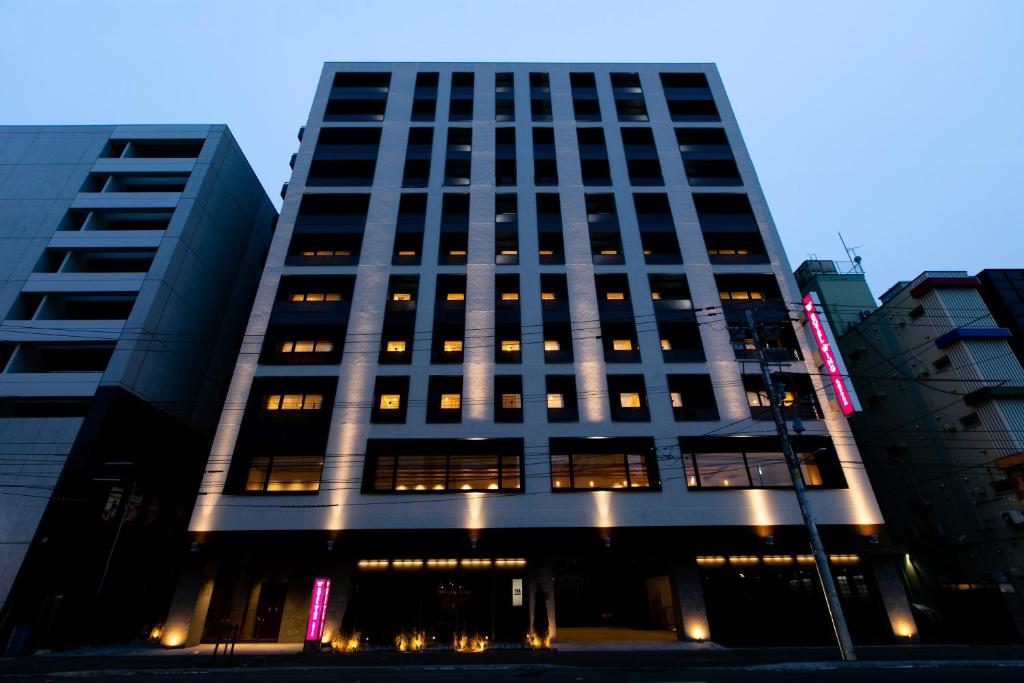 a tall building with lit windows in a city at Hotel Wing International Sapporo Susukino in Sapporo