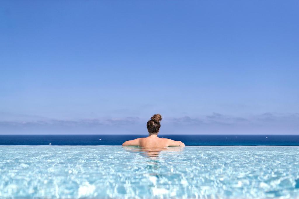 a woman sitting in the water in the ocean at Posia Retreat & Spa UNA Esperienze in San Foca