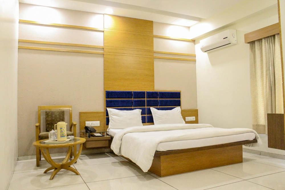 a bedroom with a large bed with a blue headboard at Hotel Apex Inn in Vapi