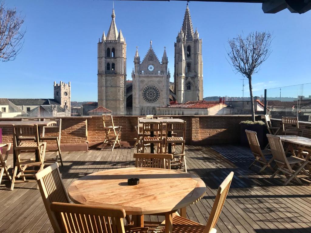 een houten tafel en stoelen op een dak met twee torens bij Camarote Hotel in León