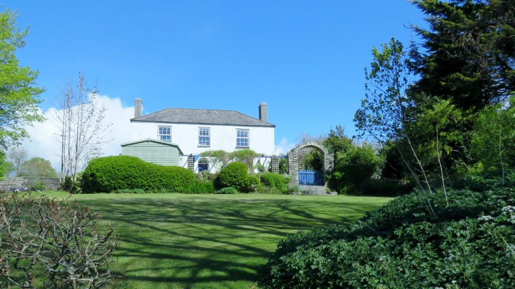 uma casa branca com um jardim verde com árvores em Kilna BnB em Saltash