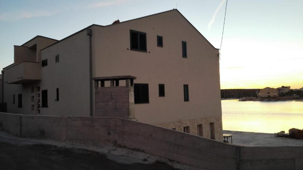 a large white building next to a body of water at Stara Kuća Apartments in Šimuni