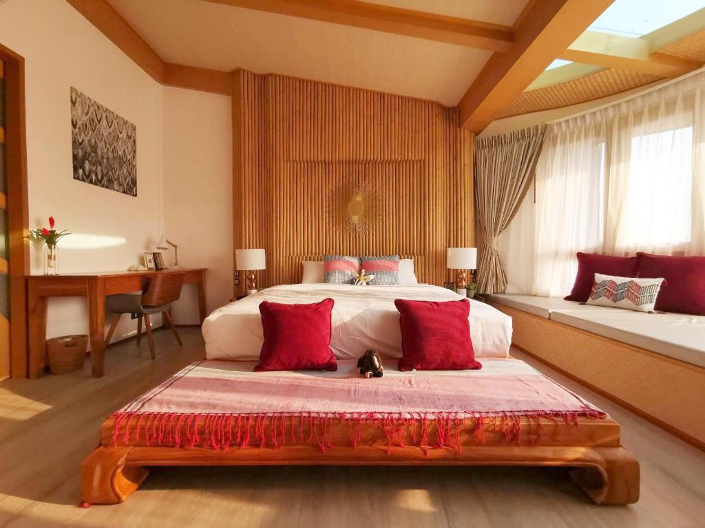 een slaapkamer met een groot bed met rode kussens bij Pannana Cha-am in Cha Am