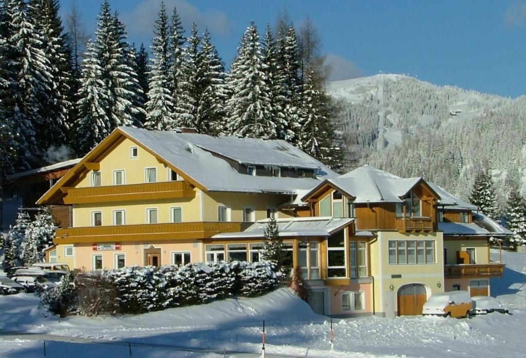 una grande casa nella neve con la neve di Hotel Gasthof Buchbauer a Bad Sankt Leonhard im Lavanttal