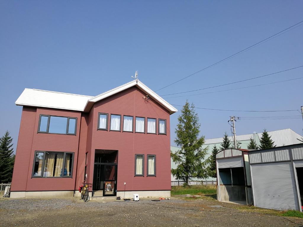 una casa roja con un garaje delante en Other Side House en Nakafurano