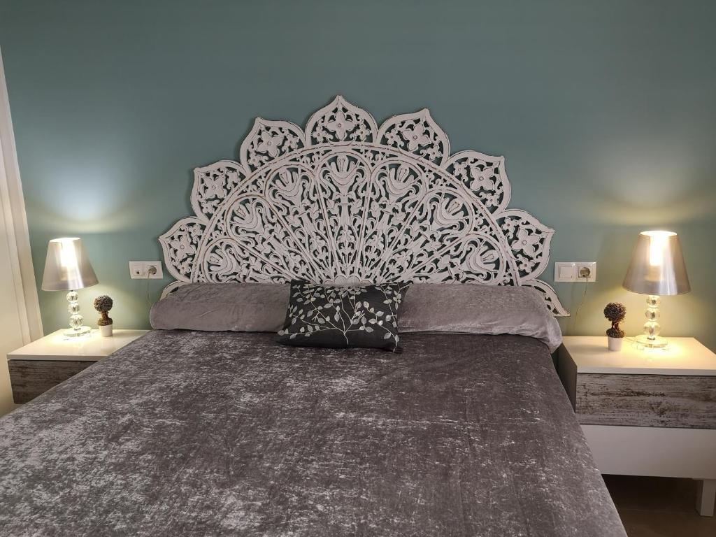 a bedroom with a large bed and two lamps at Piso Sevilla in Gelves