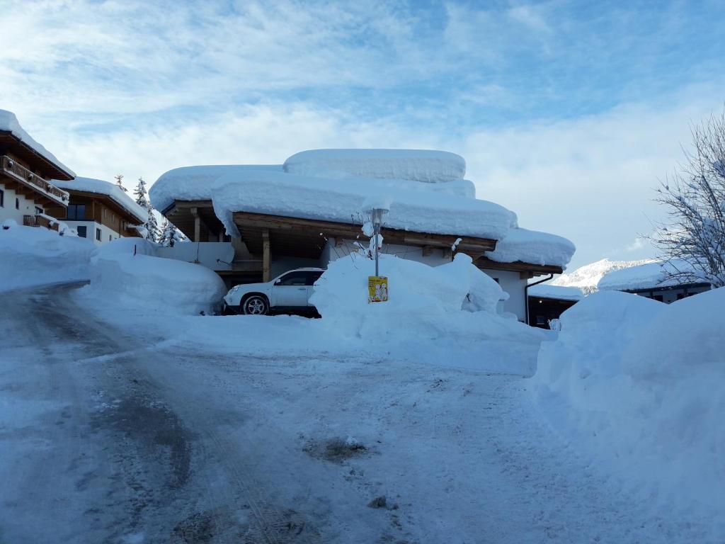 ein im Schnee vergrabenes Auto neben einem Haus in der Unterkunft Ferienwohnung Heissl in Fieberbrunn