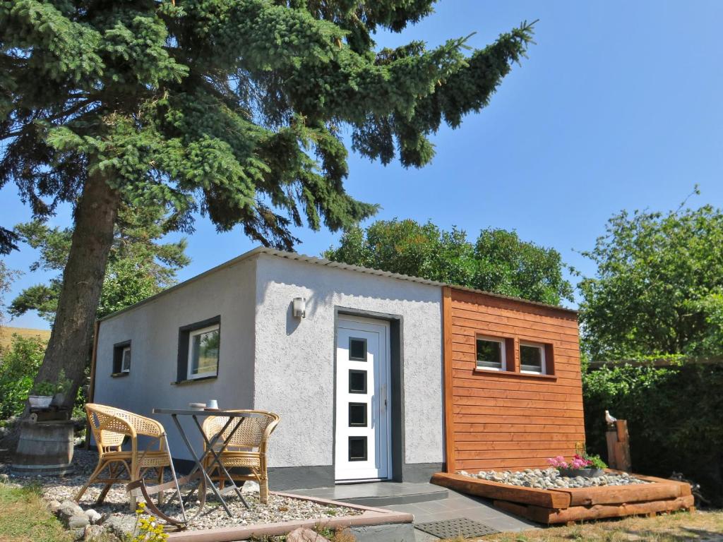 une petite maison sur une terrasse avec une table et des chaises dans l'établissement Bülows kleines Ferienhaus, à Thiessow