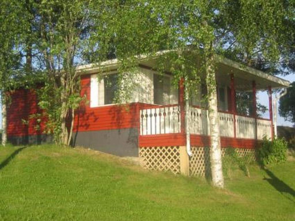 een huis met een rood-wit hek in een veld bij Holiday Home Viljamaan lomamökit 2 by Interhome in Vaskivesi