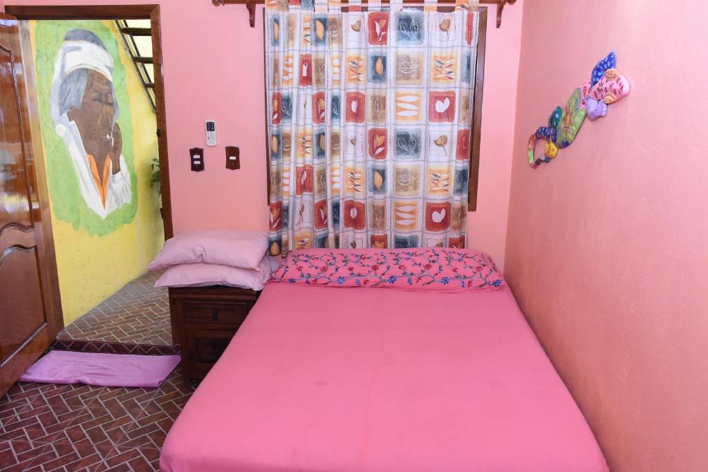 Habitación de color rosa con cama. en Cancun Guest House 1, en Cancún