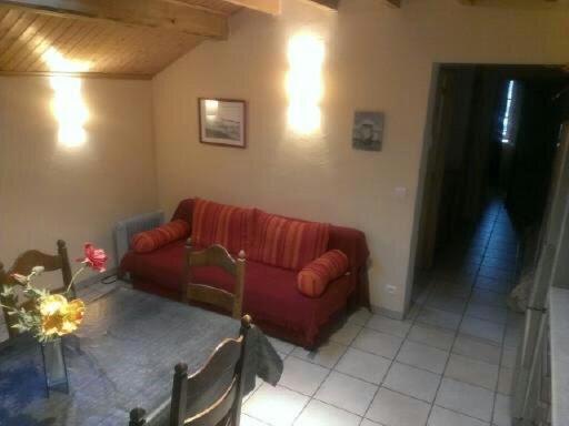 Saint-Martin-en-VercorsにあるGîte La Morandièreのリビングルーム(赤いソファ、テーブル付)