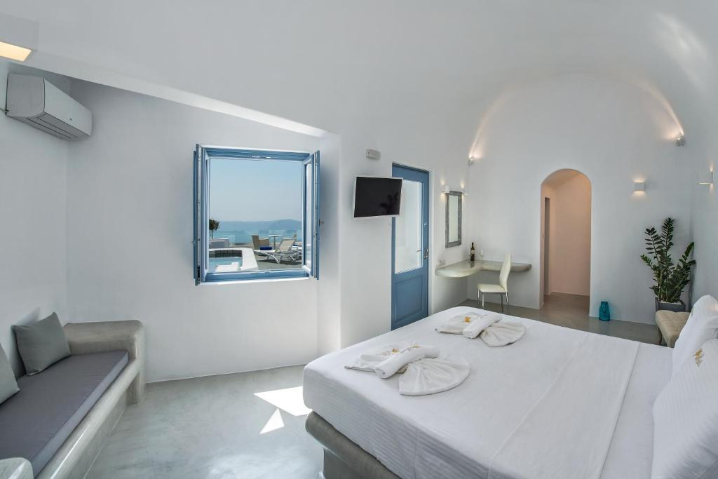 a white bedroom with a bed and a window at Pegasus Spa Hotel in Imerovigli