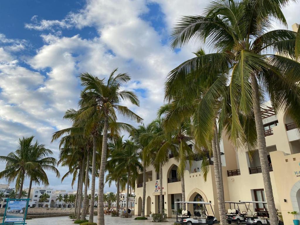 a group of palm trees in front of a building at Purple Lily Studio Hawana Lagoons Salalah in Salalah