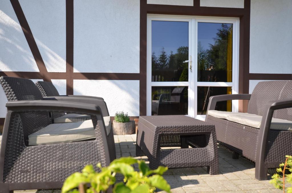 a patio with wicker chairs and a table and a window at Cztery Wiatry in Jarosławiec