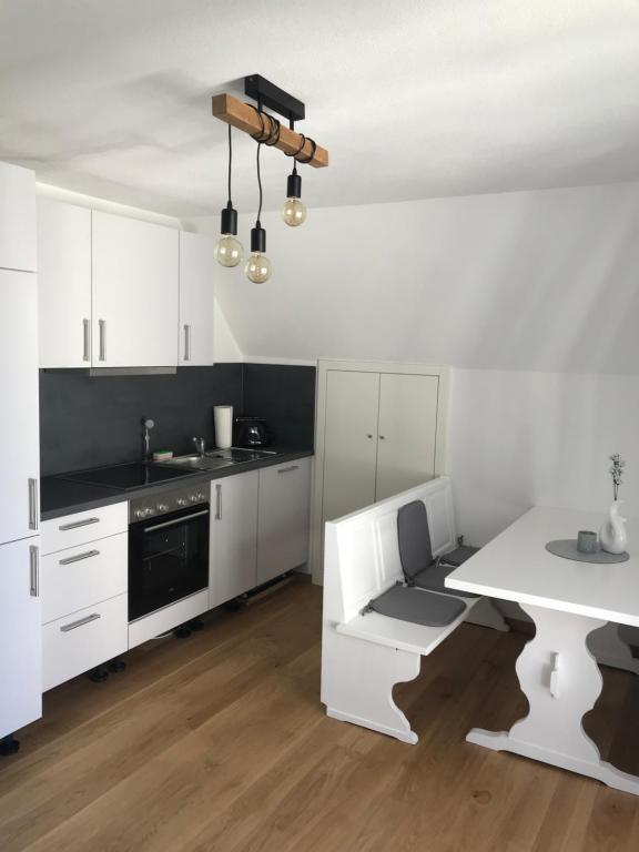 バート・ヴェーリスホーフェンにあるFühl dich wie daheimの白いキャビネット、白いテーブル、白いテーブル付きのキッチンが備わります。