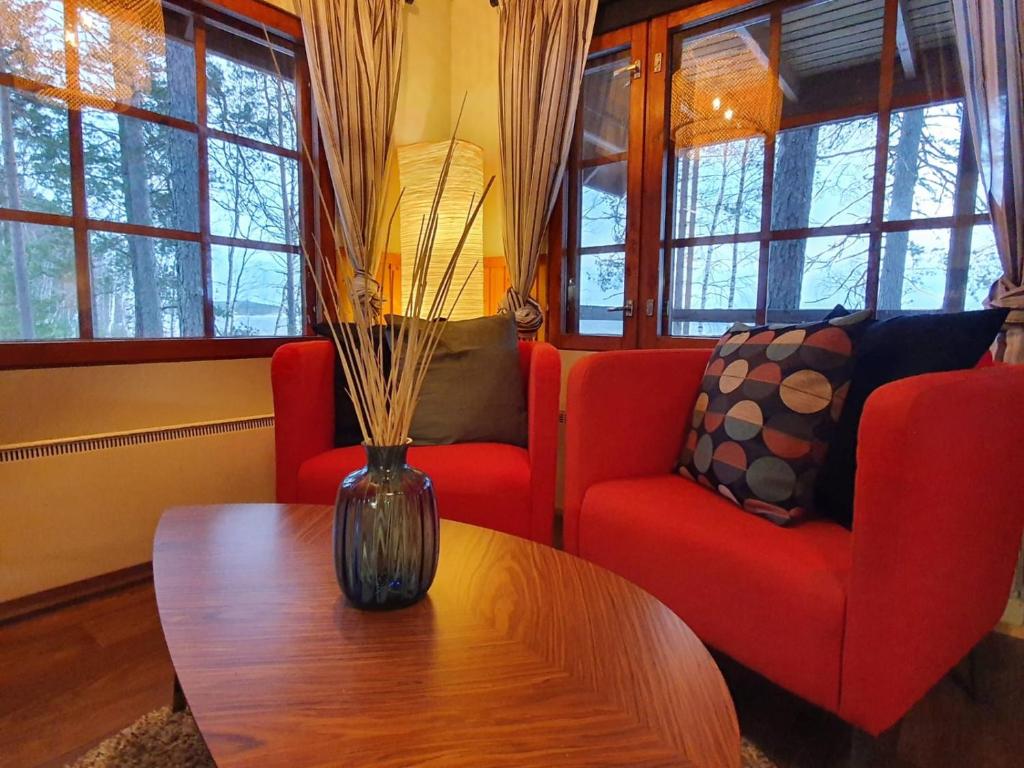 a living room with red chairs and a vase on a table at Koskenselän Lomakylä in Puumala