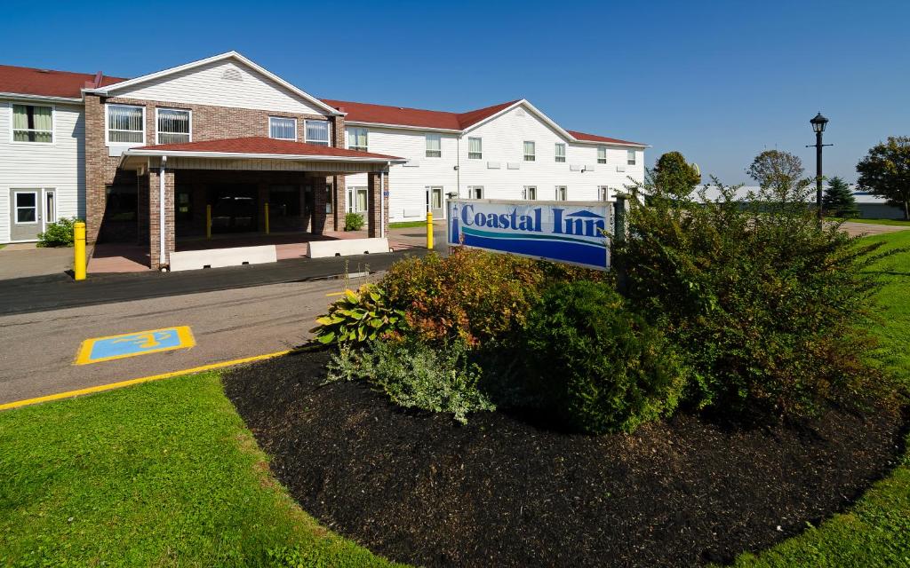 a building with a sign in front of a house at Coastal Inn Sackville in Sackville
