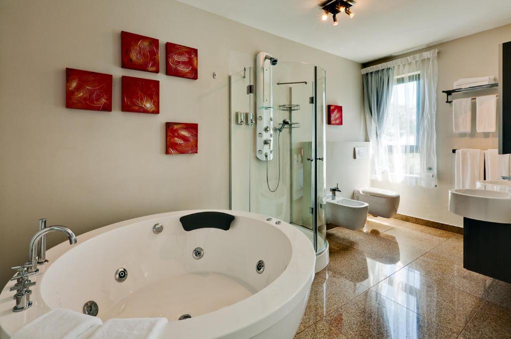 La salle de bains est pourvue d'une grande baignoire blanche et d'une douche. dans l'établissement Camps Bay Ruby Suite, au Cap