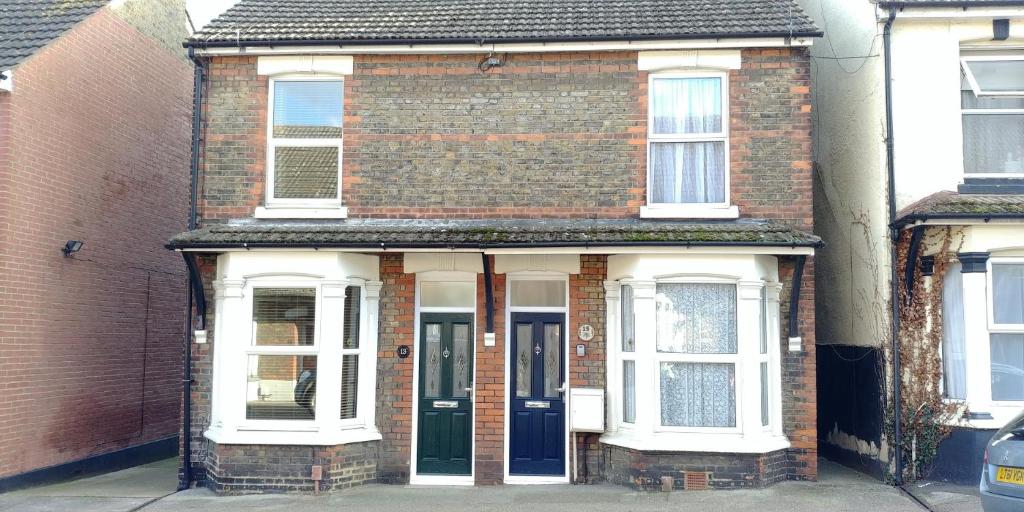 une vieille maison en briques avec une porte bleue dans l'établissement Victoria Road, comfortable 3 bedroom houses with fast Wi-Fi, à Sittingbourne