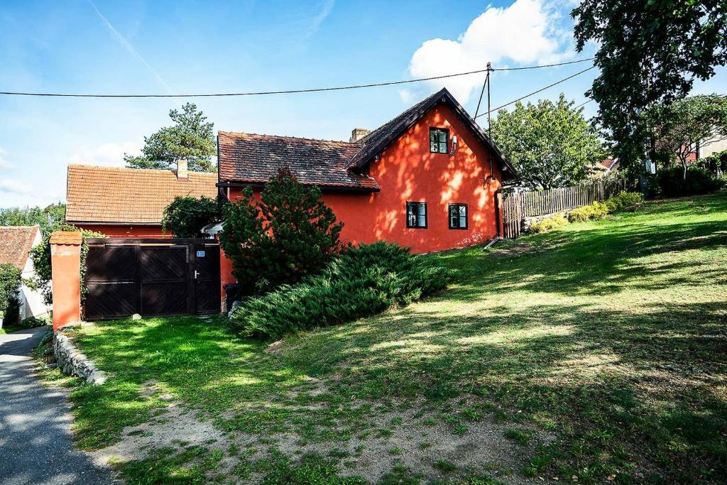 une maison rouge sur une colline avec une cour verdoyante dans l'établissement Rusty's Cottage, à Sedlčany