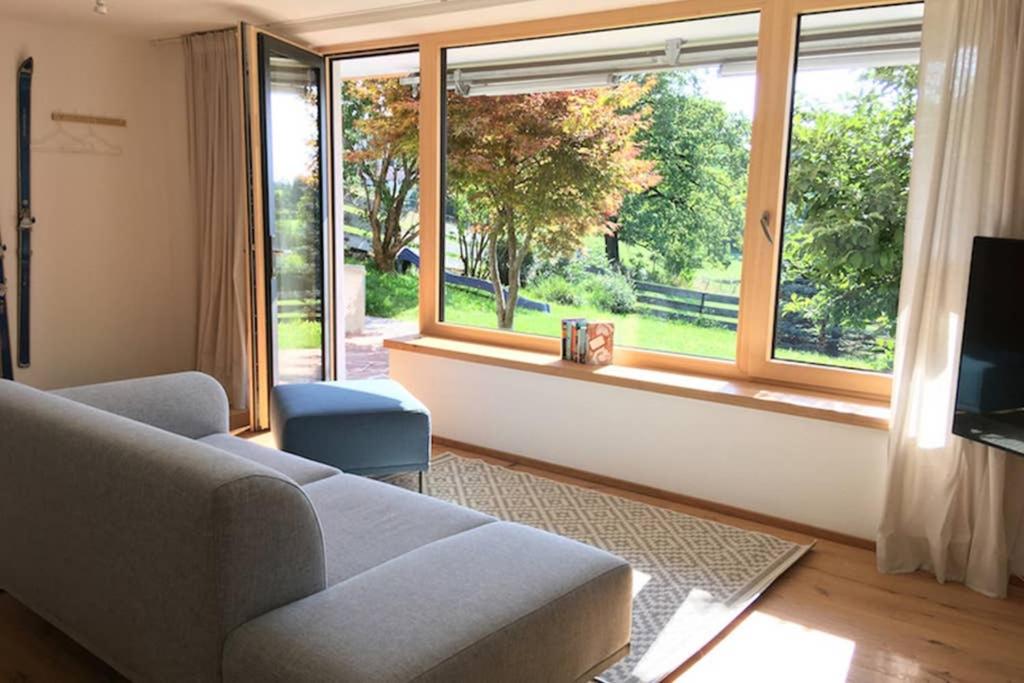 a living room with a couch and a large window at Apartment - SÜDWÄRTS - im Blauen Land in Murnau am Staffelsee