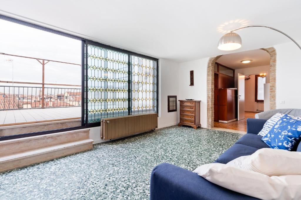 ein Wohnzimmer mit einem blauen Sofa und einem großen Fenster in der Unterkunft Ponte di Rialto Penthouse with Panoramic Terrace in Venedig