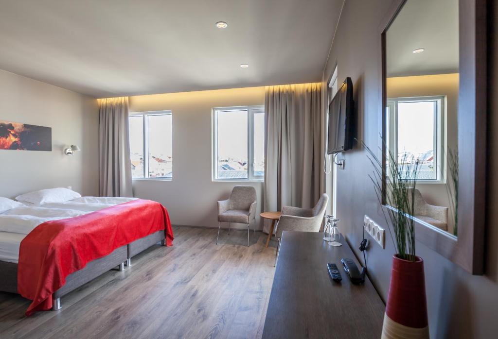 una camera d'albergo con un letto con una coperta rossa di Hotel Vestmannaeyjar a Vestmannaeyjar