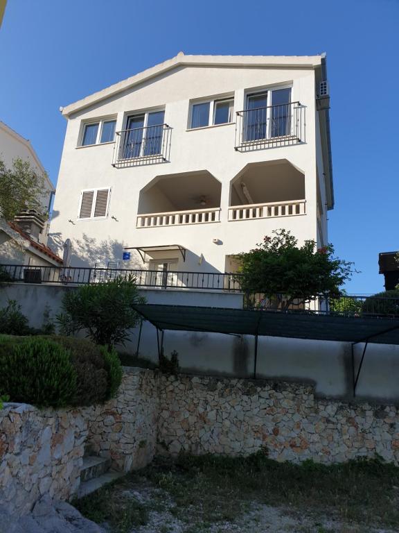 a white building with balconies on a stone wall at Apartments Zdenka in Vinišće