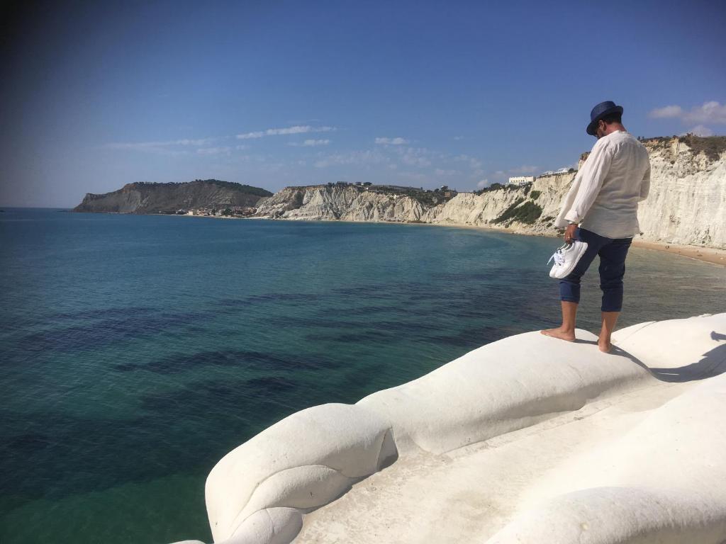 um homem de pé numa rocha perto da água em villa mediterranea em Realmonte