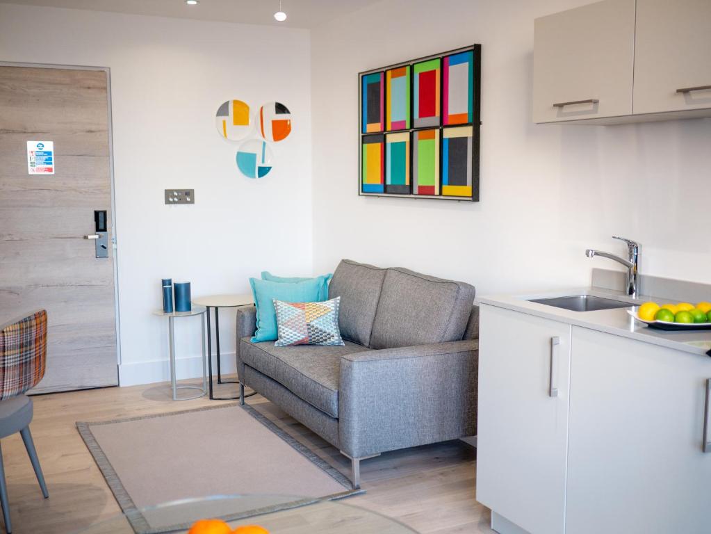 a living room with a couch and a kitchen with a sink at Q Square by Supercity Aparthotels in Brighton & Hove