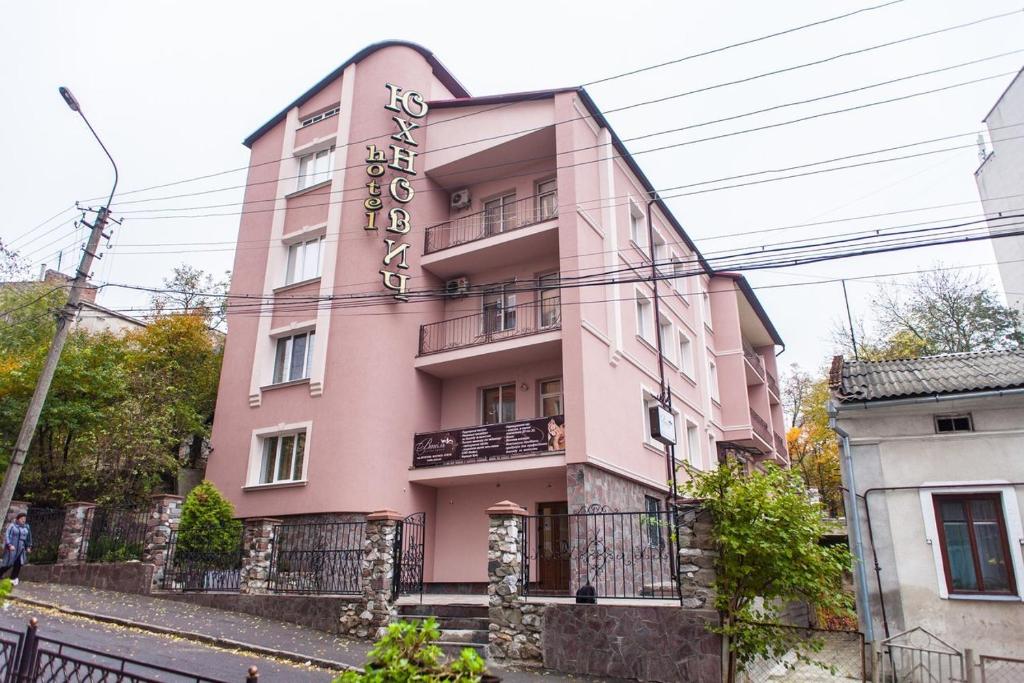 ein rosafarbenes Gebäude mit einem Schild darauf in der Unterkunft Hotel Complex Uhnovych in Ternopil