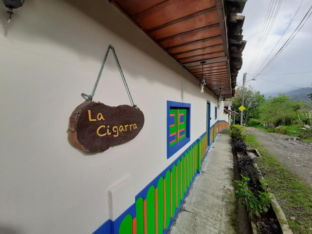 Een bord waarop staat dat de klerk aan de zijkant van een gebouw hangt. bij La Cigarra Casa de Huéspedes in Salento