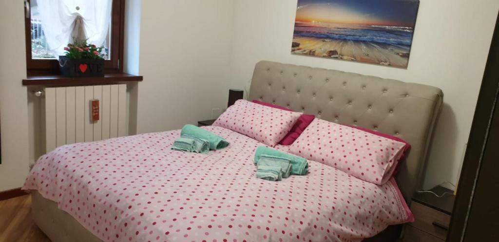 una camera da letto con un letto con cuscini rosa e verdi di Casa Ramus Valle Camonica a 30 km dal Passo Tonale a Edolo